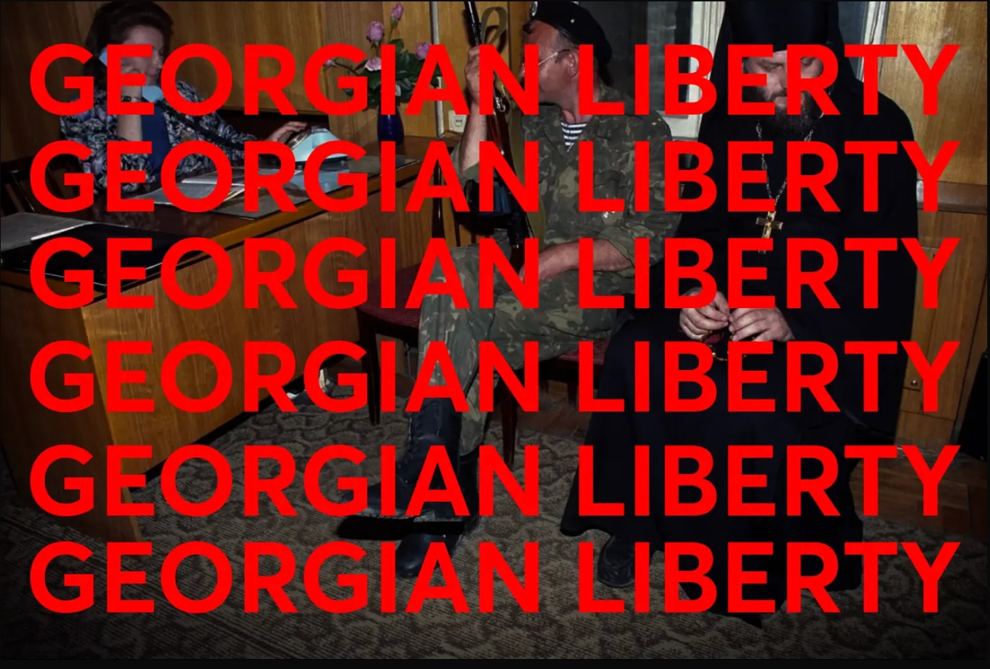 The words Georgian Liberty repeated in red over a photograph of a soldier and a priest seated in an office